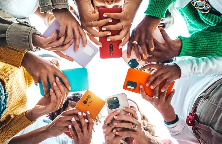 Group of young people using smart mobile phone device outside