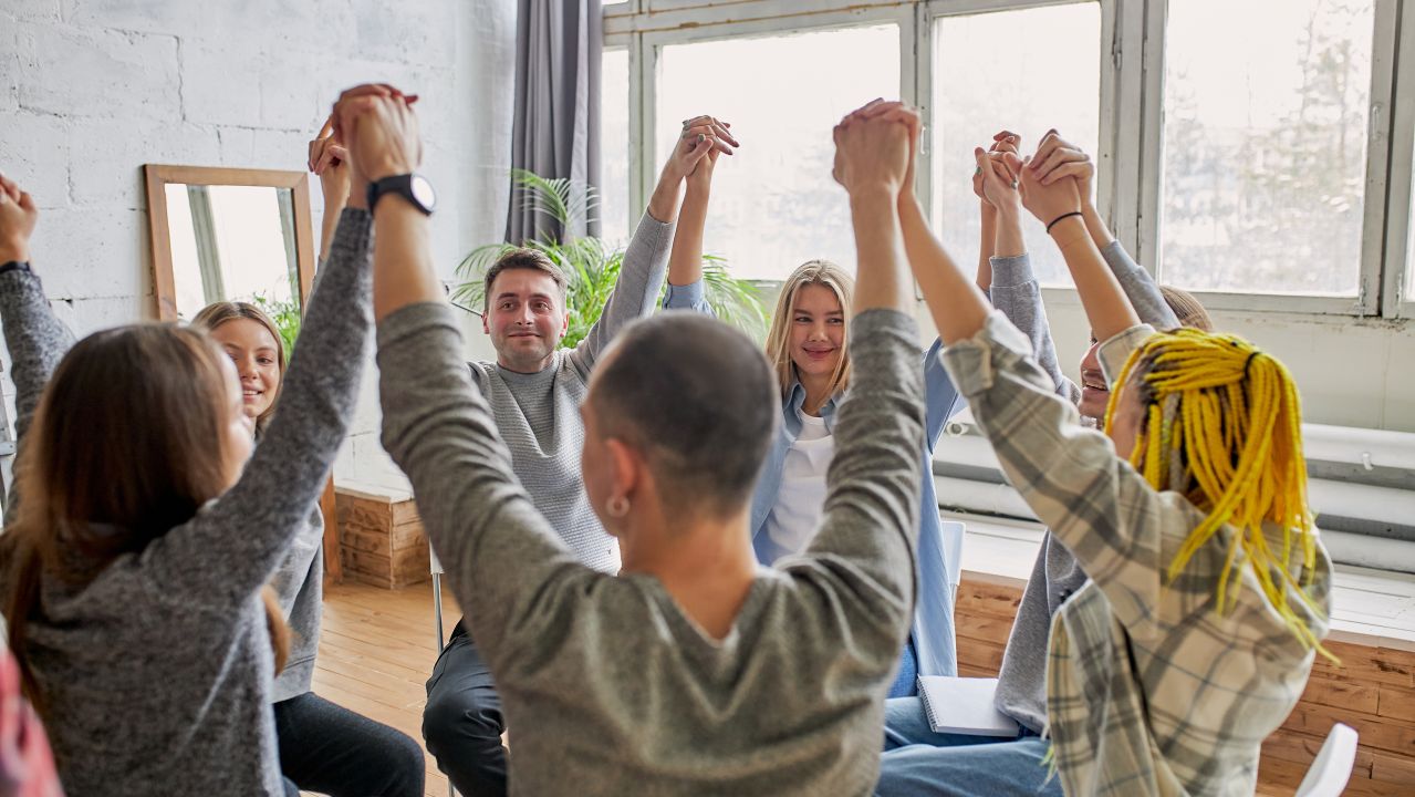 A group therapy session where folks are raising their arms up.